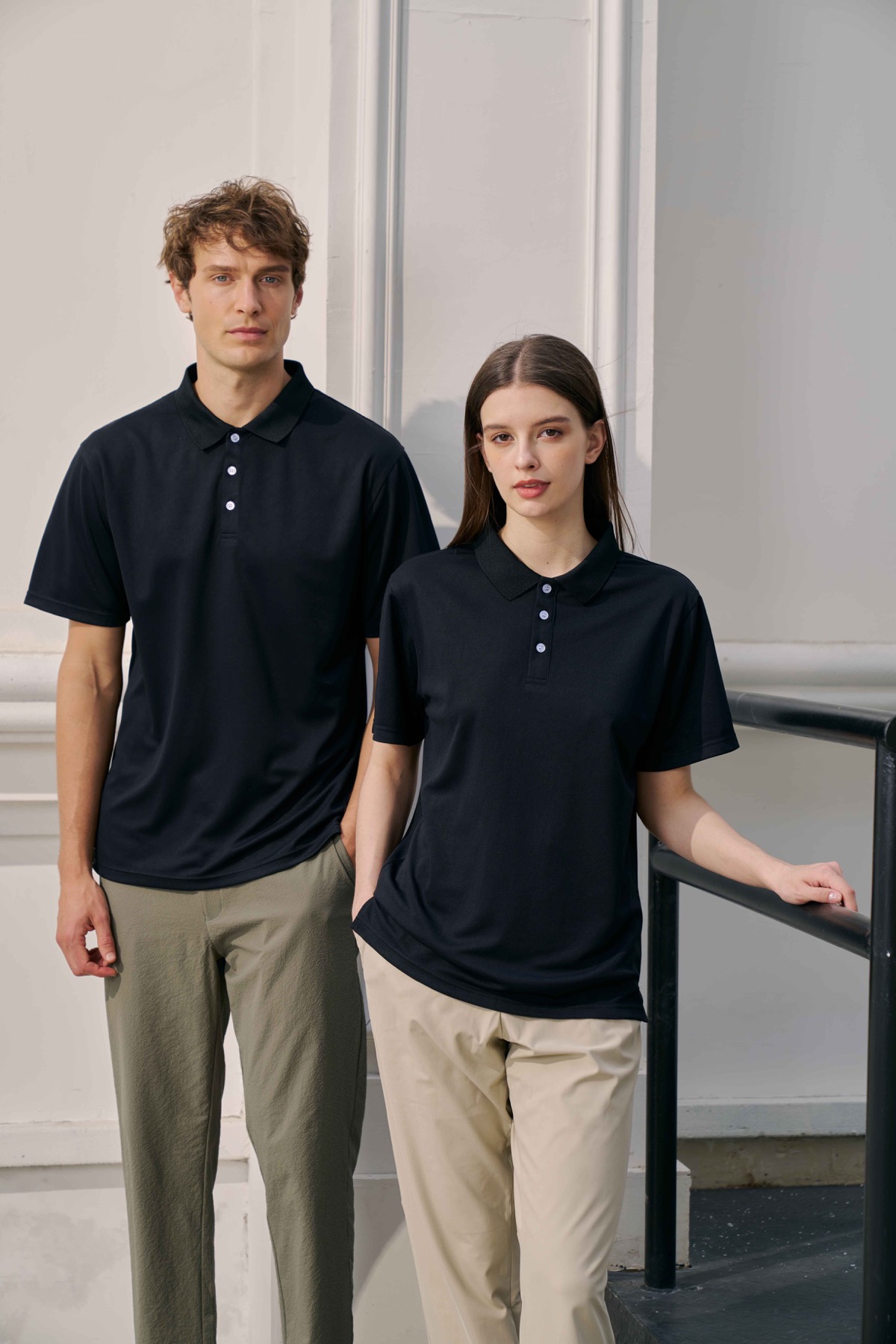 Models wearing black recycled microfiber polo shirts